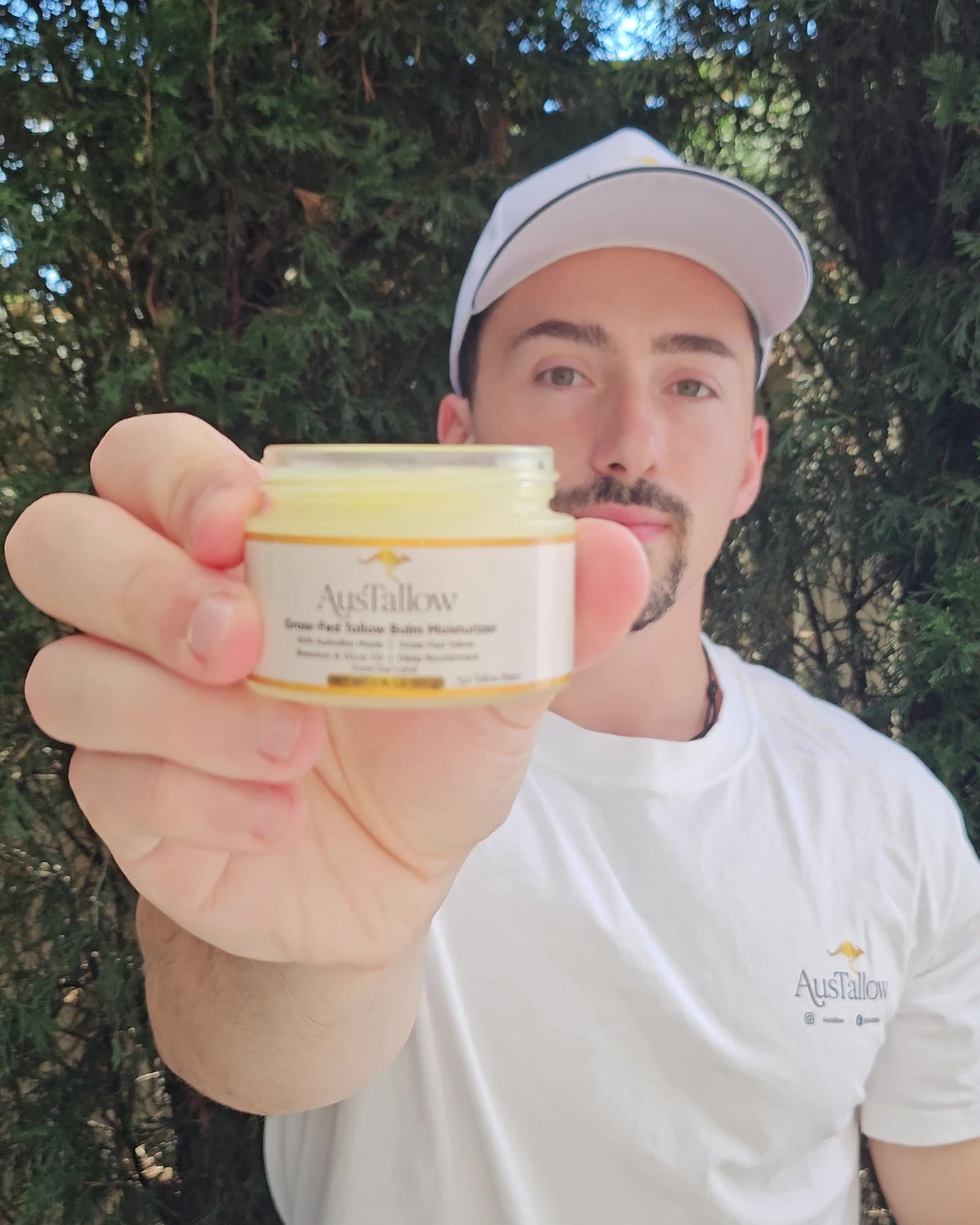 AusTallow founder Johnny holding an open 50g jar of grass-fed tallow balm, made in Sydney, Australia