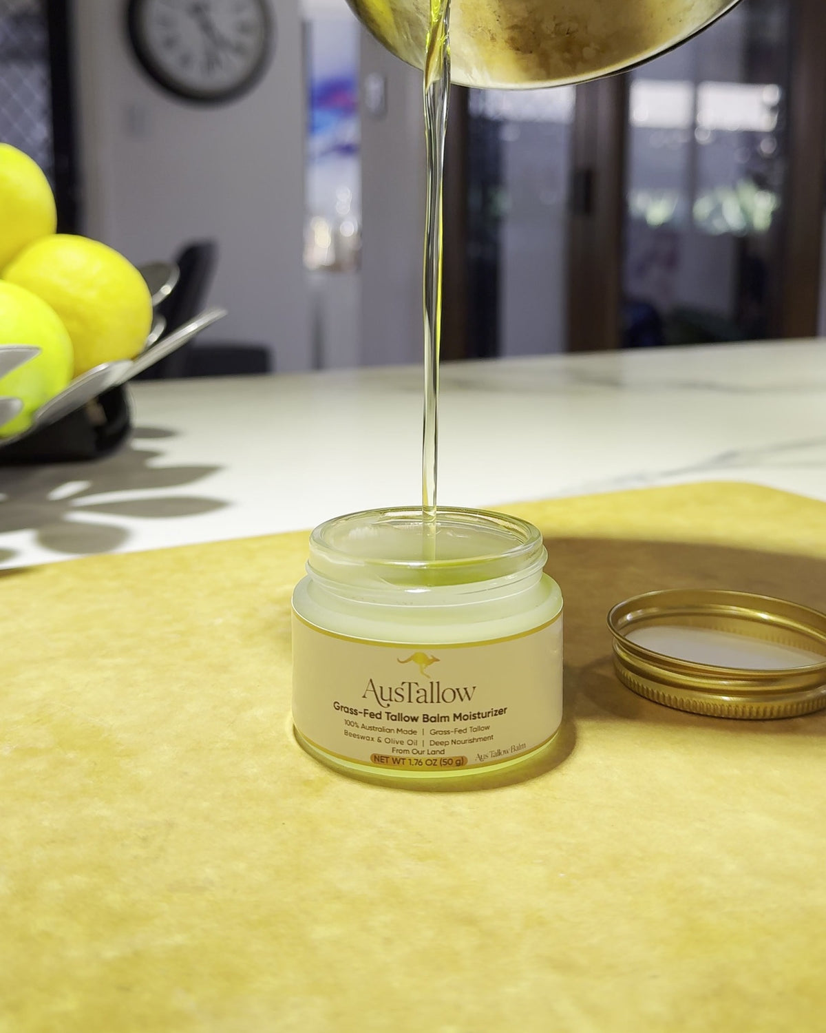 Melted tallow balm being poured by hand into an AusTallow glass jar in a small-batch kitchen in Sydney