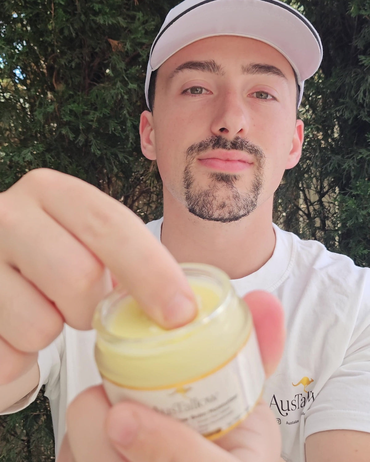 Fingertip scooping a pea-sized amount of AusTallow grass-fed tallow balm from the open 50g glass jar
